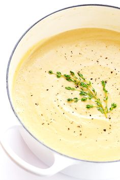 a white bowl filled with soup and garnished with some green sprigs