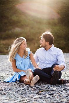 a man and woman are sitting on the ground looking at each other as they smile