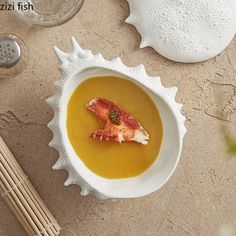 a white bowl filled with soup on top of a table next to chopsticks