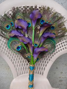 a vase filled with purple flowers and peacock feathers