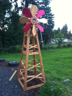 a wooden windmill sitting on top of a lush green field