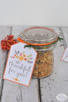 a glass jar filled with granola sitting on top of a wooden table next to an orange and white tag