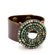 a brown leather bracelet with beads on the clasp and an open circle in the middle