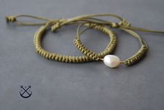 two bracelets with white pearls are on a gray surface