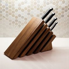 a set of knives sitting on top of a wooden block in front of a tiled wall