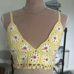 a mannequin wearing a yellow crochet top with white and orange flowers