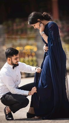 a man kneeling down next to a woman in a blue dress