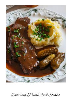 a white plate topped with meat and potatoes covered in gravy next to mashed potatoes