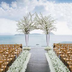 two tall vases with white flowers are on the end of an outdoor ceremony set up