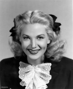 an old black and white photo of a woman with a big bow around her neck