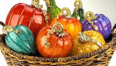 a basket filled with lots of colorful glass pumpkins