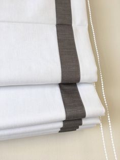 white and grey sheets are folded on top of each other with a chain hanging from the side