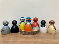 a group of small wooden birds sitting on top of a wooden table next to a white wall