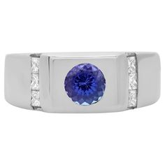 This stunning men's ring is crafted in 14K white gold and features a center stone: round cut Tanzanite weighing 0.85 carat with accents stones: 6 princess cut white diamonds weighing 0.50 carat. Ring size: 10.5. Band width: 9.33 mm. Total weight: 16.15 grams. Comes with a presentable gift box. Diamond Mens Ring, 6 Princess, Mens Ring, Men's Ring, Princess Cut, Tanzania, Diamond White, Class Ring, Sapphire Ring