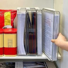 a book shelf filled with files and folders next to a red bag on top of it