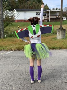 a woman in a green tutu and purple socks is holding up a toy plane