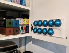 a kitchen cabinet with blue ornaments on the door knobs and shelves in front of it