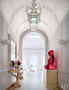 the hallway is decorated in white and has pink vases on pedestals next to it