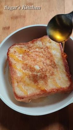 a spoon is being drizzled over a grilled cheese sandwich in a bowl