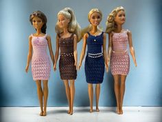 three barbie dolls standing next to each other in front of a blue wall and wearing dresses