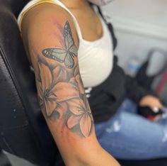 a woman sitting in a car with a butterfly on her arm and flowers around her wrist