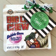 a bag of big chew gum sitting on top of a wooden floor next to a ribbon