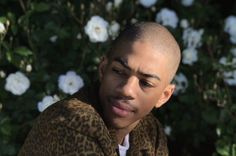 a close up of a person wearing a leopard print jacket with flowers in the background