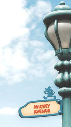 a street light with a sign for mickey's avenue in front of a cloudy blue sky