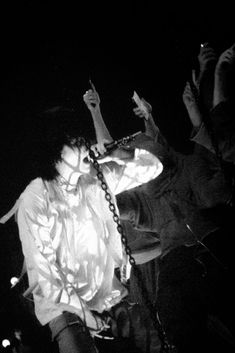 a woman holding a cell phone up to her ear while standing in front of a microphone