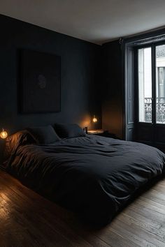 a bedroom with black walls and wooden flooring is lit up by two small lights