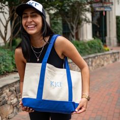 a woman holding a tote bag with the letter kti on it and smiling