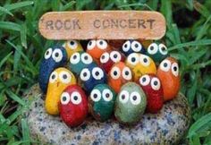 a group of rocks with eyes painted on them and a sign that says root concert