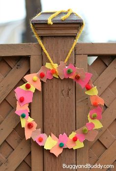 a paper flower wreath hanging on a wooden fence with a chain attached to the door