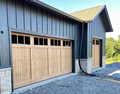 two garage doors are open on the side of a building with gravel in front of them