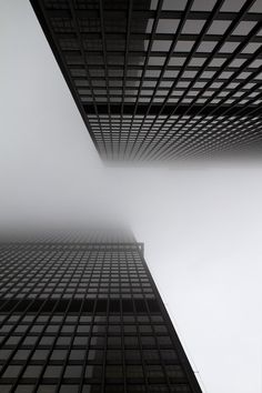 two tall buildings in the middle of a foggy sky