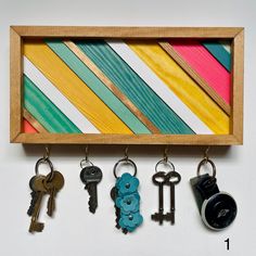 several keys are hanging in a wooden frame with key hooks on the bottom and below