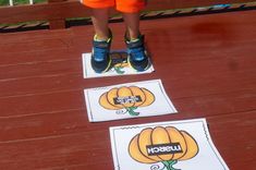 a young boy standing on top of two matching mats with pumpkins and words that spell out the word