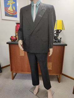 This is an 80s suit by the Pierre Cardin label in a charcoal grey medium weight wool fabric. The inside pocket says 107cm short. The jacket is very well cut and finished, is a box shape somewhat oversized in a loose fit, has wide sharp lapels, firm shoulder padding, a double breasted closure and plenty of internal pockets and is charcoal grey lined. The pants are a slim cut with side seam pockets and two small pleats at the front. There is a good seam allowance at the hem should you need it for Gray Double-breasted Suit For Business, Gray Double-breasted Business Suits, Gray Double-breasted Formal Suit, Classic Gray Double-breasted Suit, Gray Fitted Double-breasted Suits, Vintage Double Breasted Suit With Notch Lapel For Work, Vintage Double-breasted Suits For Workwear, Vintage Three-piece Suit With Suit Collar For Business, Vintage Black Suits For Business