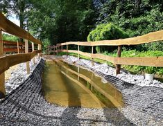 there is a wooden bridge that has water running through it and rocks on the ground