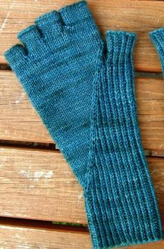 a pair of blue knitted gloves sitting on top of a wooden bench next to each other