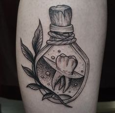 a tattoo with a glass jar filled with liquid and a fist in the middle, surrounded by leaves