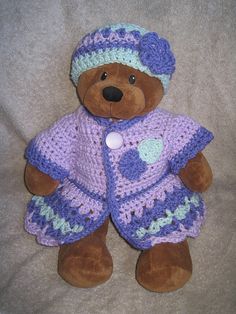 a brown teddy bear wearing a purple crocheted outfit