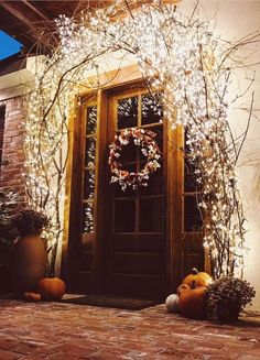 the front door is decorated with white lights and pumpkins