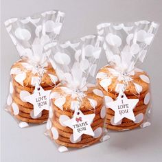 three cookies wrapped in clear cellophane with white polka dots and stars on them