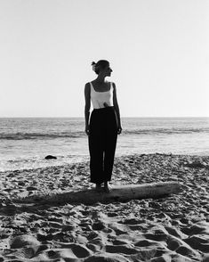 a woman standing on top of a surfboard in the sand