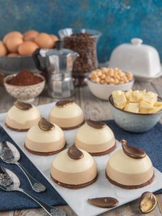 there are many desserts on the table with spoons and bowls in front of them