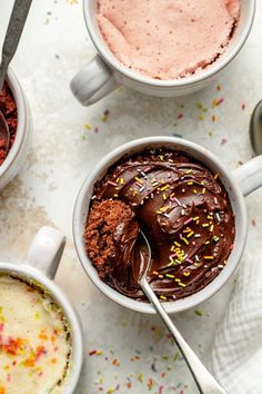 three mugs filled with different types of ice cream and chocolate frosting on top of confetti sprinkles