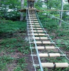 a ladder made out of wooden logs in the woods with ropes attached to it's sides