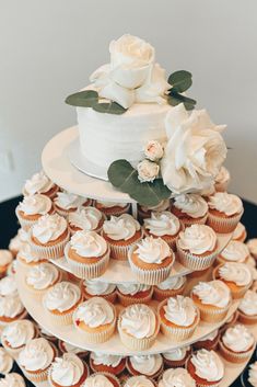 a wedding cake and cupcakes are stacked on top of each other with white flowers