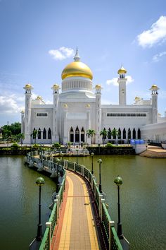 a large white building with a gold dome on top next to a body of water